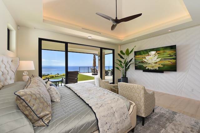 bedroom featuring ceiling fan, a tray ceiling, and access to exterior