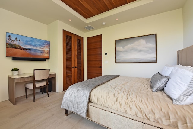 bedroom featuring a closet, wood ceiling, a raised ceiling, and light hardwood / wood-style floors