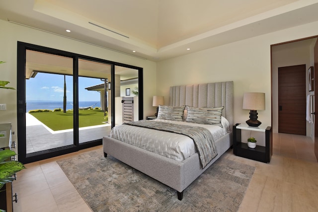 bedroom with light hardwood / wood-style floors, access to outside, and a water view