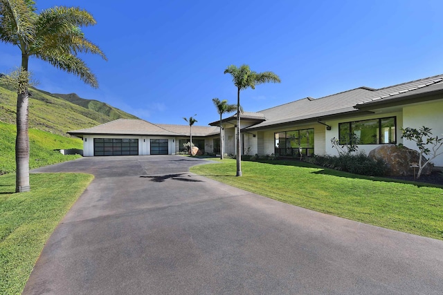 ranch-style home with a garage, a mountain view, and a front lawn