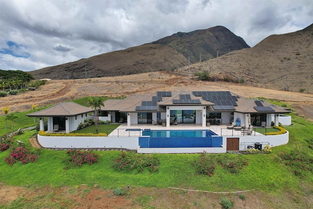 exterior space with a mountain view, a patio area, solar panels, and a yard