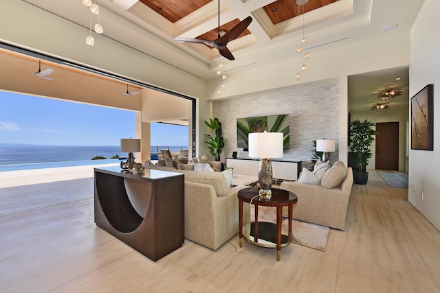 living room featuring ceiling fan, beamed ceiling, a view of the beach, coffered ceiling, and a towering ceiling