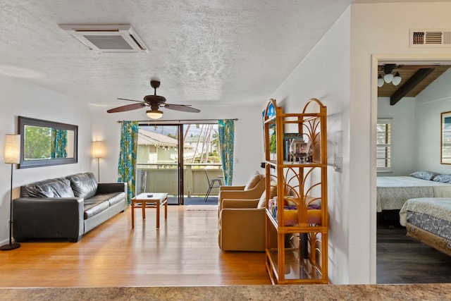 living room featuring lofted ceiling with beams, a textured ceiling, hardwood / wood-style flooring, and ceiling fan