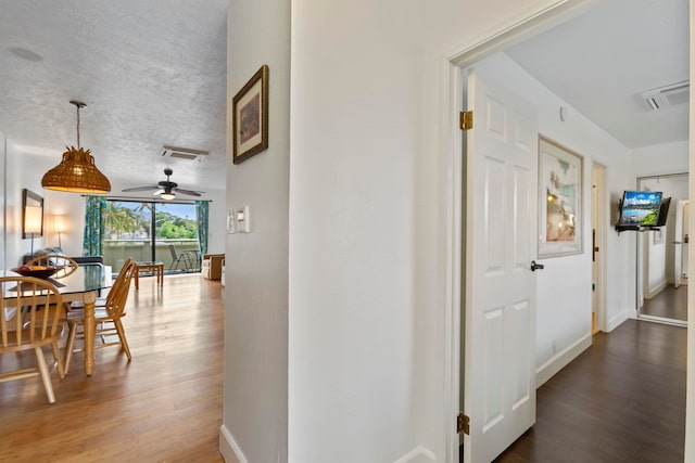 hall with wood-type flooring and a textured ceiling