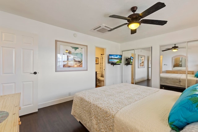 bedroom featuring ceiling fan, dark hardwood / wood-style flooring, multiple closets, and ensuite bath