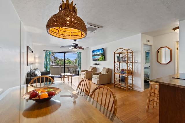 dining room with ceiling fan, light hardwood / wood-style flooring, and a textured ceiling