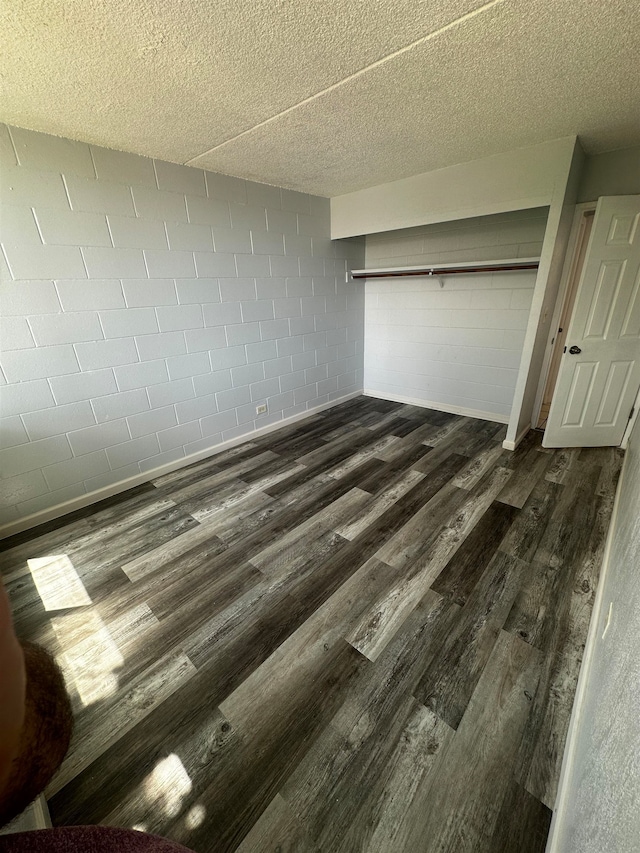 unfurnished bedroom with a textured ceiling and dark hardwood / wood-style flooring