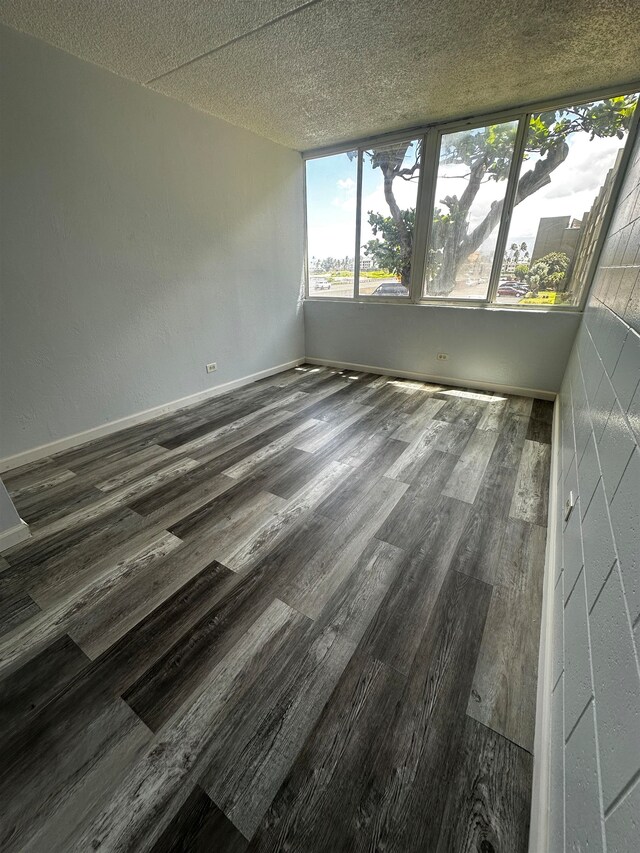 unfurnished room featuring a textured ceiling and dark hardwood / wood-style floors