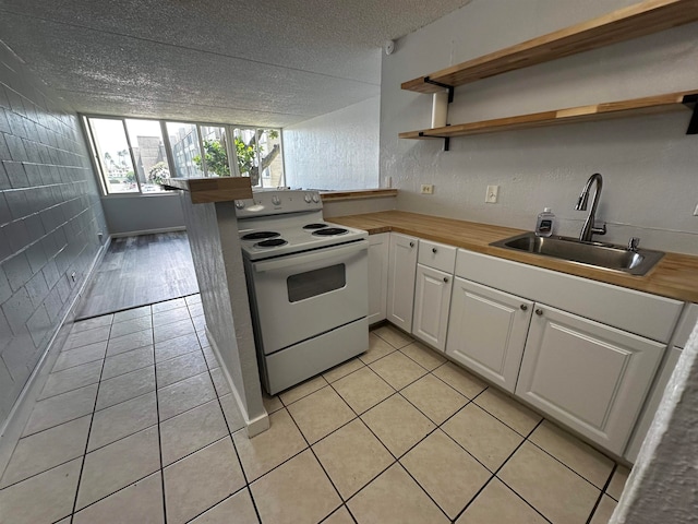 kitchen featuring butcher block counters, sink, white electric range oven, white cabinetry, and a textured ceiling