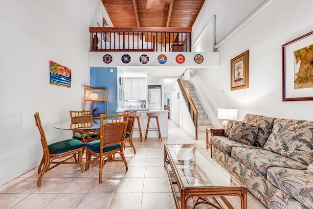 living room featuring light tile patterned floors, stairs, wood ceiling, and a towering ceiling