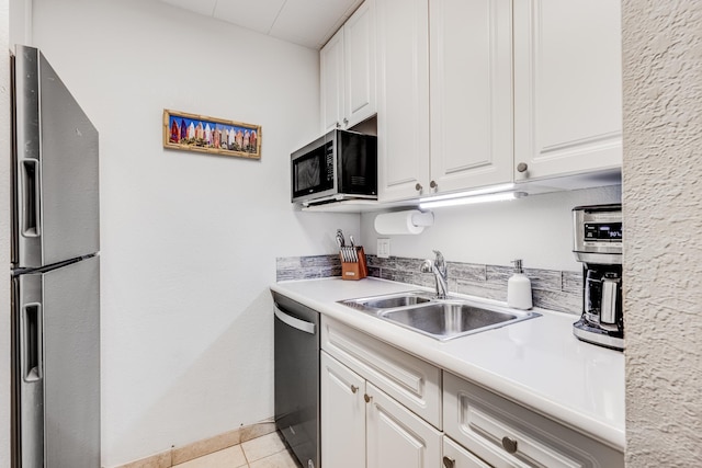kitchen featuring light tile patterned floors, stainless steel appliances, white cabinetry, and a sink