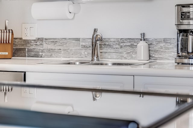 room details with white cabinetry, tasteful backsplash, and a sink