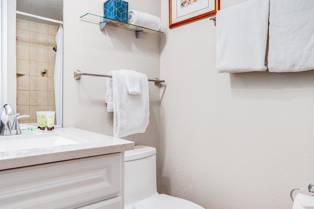 full bathroom featuring walk in shower, vanity, toilet, and a textured wall