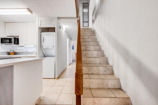 stairway with stacked washer / dryer, tile patterned flooring, and visible vents