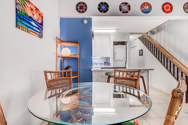 dining room featuring stairs, stacked washer and dryer, and light tile patterned floors