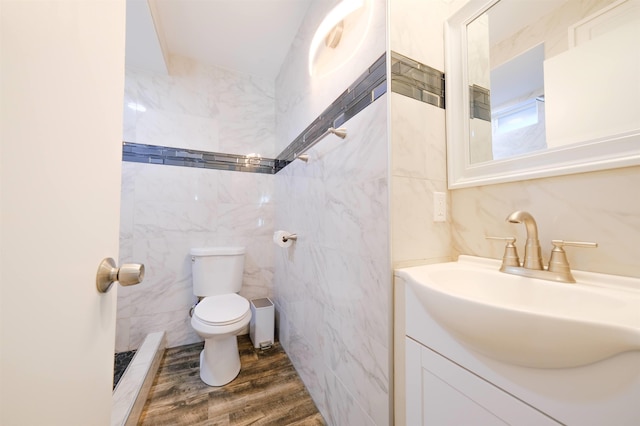 bathroom featuring wood finished floors, vanity, toilet, and tile walls