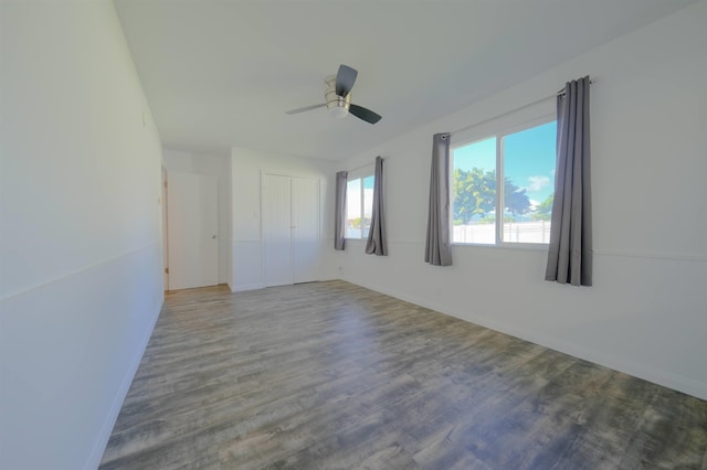 empty room with ceiling fan, wood finished floors, and baseboards