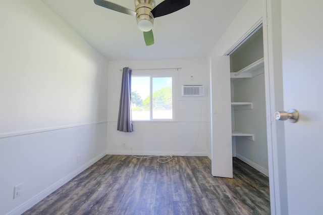 unfurnished bedroom with a ceiling fan, baseboards, wood finished floors, and a wall mounted air conditioner