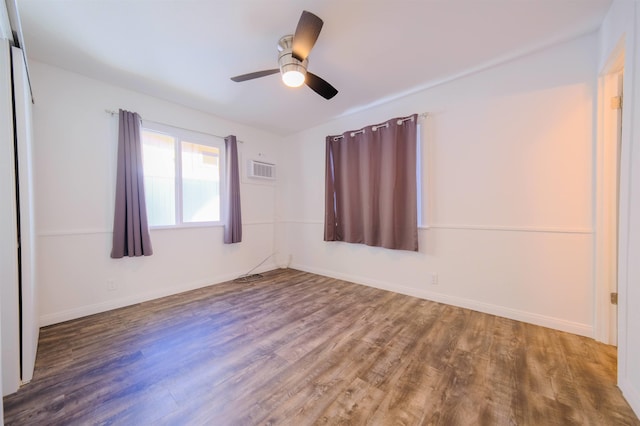 spare room with a wall mounted AC, wood finished floors, a ceiling fan, and baseboards