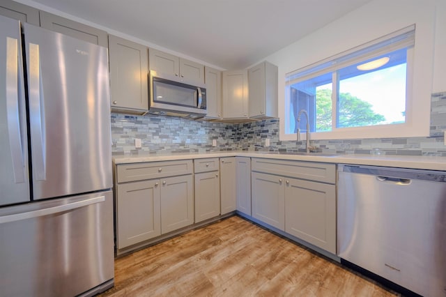 kitchen with tasteful backsplash, appliances with stainless steel finishes, gray cabinets, and a sink