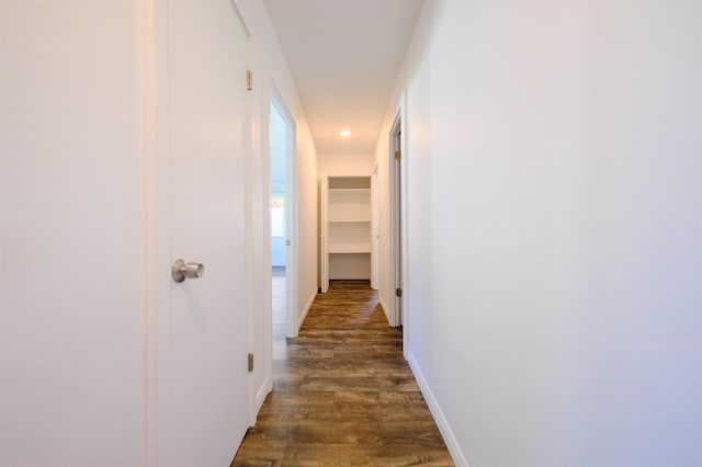 hallway featuring dark wood-type flooring and baseboards