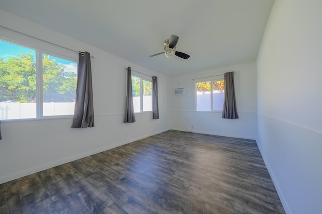 empty room featuring ceiling fan, an AC wall unit, dark wood-type flooring, and baseboards