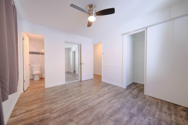 unfurnished bedroom featuring a ceiling fan, a closet, ensuite bath, and wood finished floors