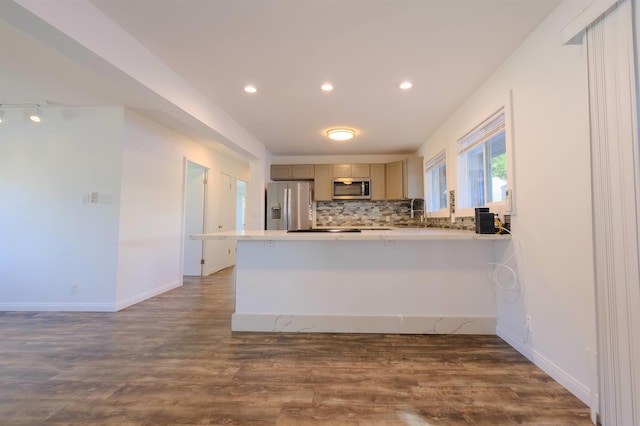 kitchen featuring a peninsula, appliances with stainless steel finishes, backsplash, and wood finished floors