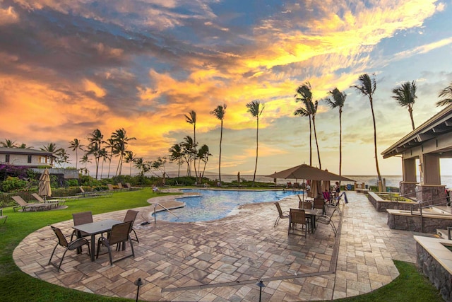 pool at dusk featuring a yard and a patio