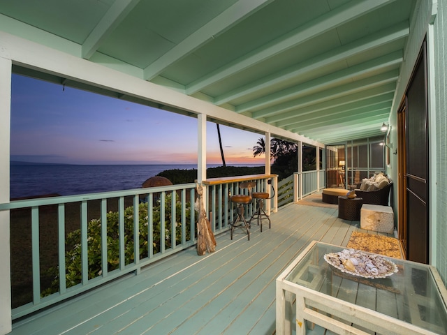 deck at dusk featuring a water view