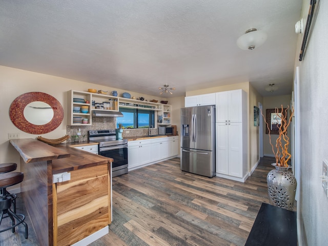 kitchen featuring tasteful backsplash, white cabinetry, appliances with stainless steel finishes, and wooden counters