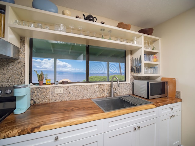 kitchen featuring tasteful backsplash, butcher block counters, white cabinetry, and sink