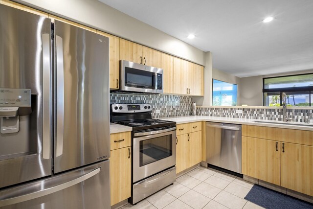 kitchen featuring sink, light brown cabinetry, light tile patterned floors, and stainless steel appliances