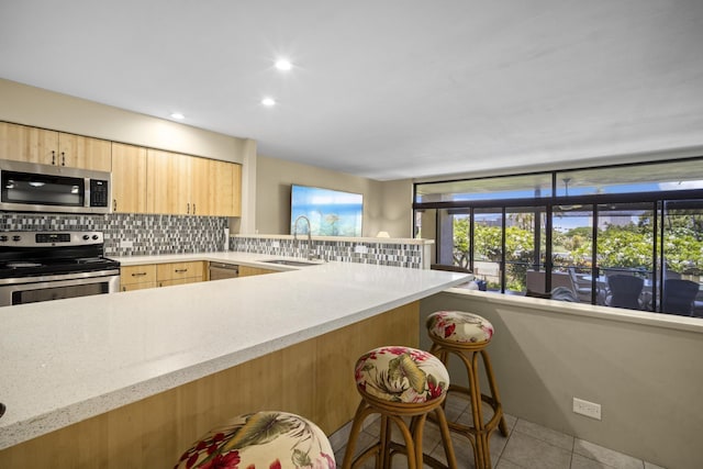 kitchen featuring appliances with stainless steel finishes, light brown cabinets, tasteful backsplash, sink, and light tile patterned floors