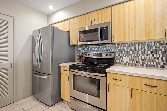 kitchen with light tile patterned flooring, backsplash, light brown cabinetry, and stainless steel appliances