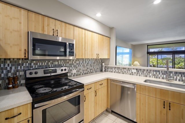 kitchen featuring appliances with stainless steel finishes, decorative backsplash, sink, light brown cabinetry, and light tile patterned floors