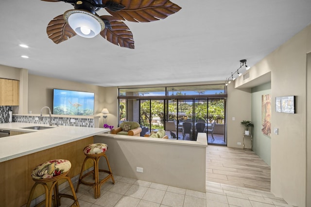 kitchen with sink, ceiling fan, kitchen peninsula, and decorative backsplash