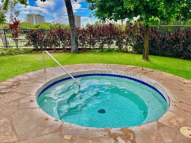 view of pool with an in ground hot tub and a lawn