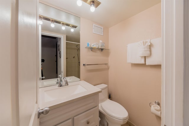 bathroom featuring toilet, vanity, and tiled shower