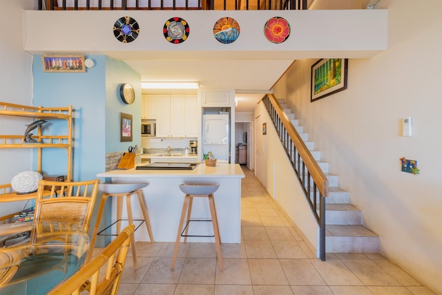 kitchen featuring a kitchen breakfast bar, white cabinetry, kitchen peninsula, and light tile patterned flooring