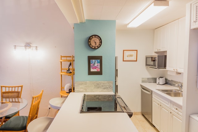 kitchen featuring appliances with stainless steel finishes, white cabinetry, sink, and light tile patterned floors