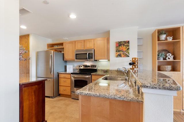 kitchen with light stone countertops, kitchen peninsula, sink, and appliances with stainless steel finishes