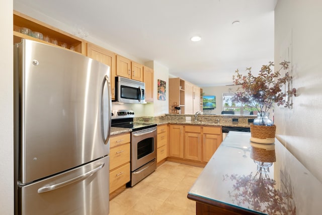 kitchen with light stone countertops, kitchen peninsula, stainless steel appliances, sink, and light brown cabinets