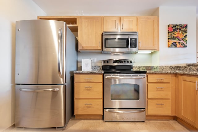 kitchen featuring appliances with stainless steel finishes, light tile patterned floors, light stone counters, and light brown cabinets