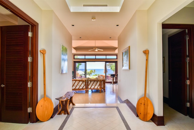 corridor featuring light tile patterned flooring and a raised ceiling