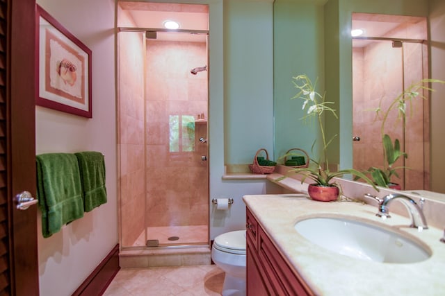 bathroom featuring tile patterned floors, vanity, toilet, and a shower with shower door