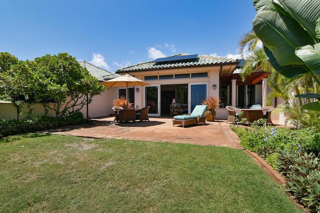 back of house with solar panels, a yard, and a patio area