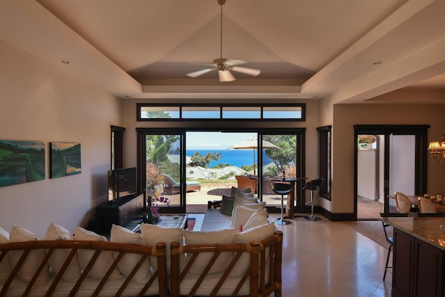 living room with ceiling fan, a high ceiling, and a tray ceiling