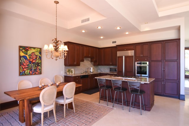 kitchen with decorative light fixtures, a center island, stainless steel appliances, and a tray ceiling