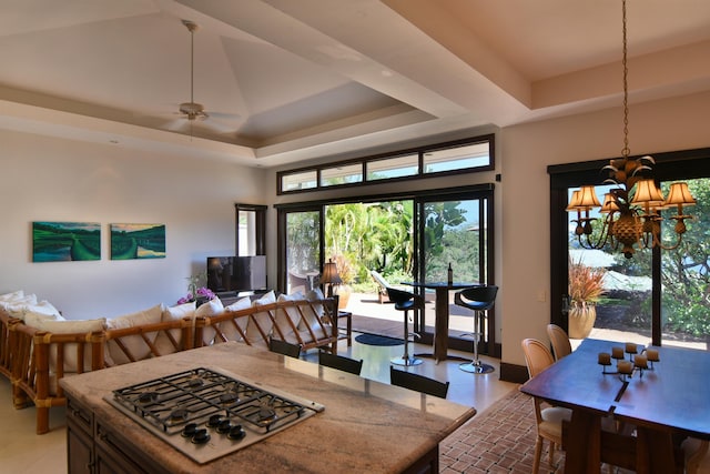 dining space with ceiling fan with notable chandelier, a raised ceiling, and a towering ceiling